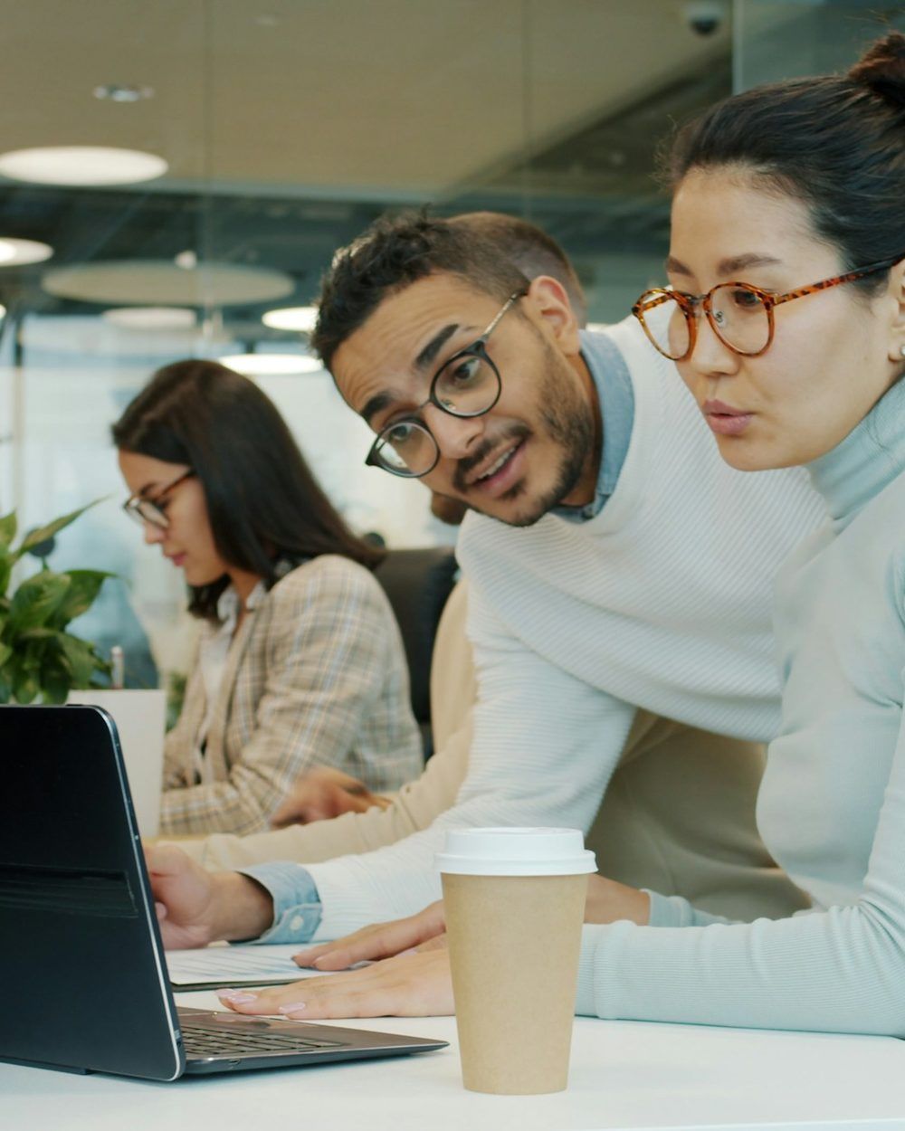 A manager and a colleague reviewing work on one laptop